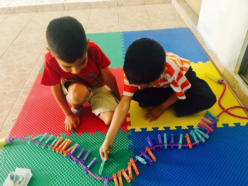 Dos niños jugando con pinzas de colores en el consultorio Para Elisa en Chihuahua
