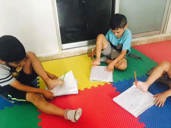 Niños dibujando con los pies durante una actividad de psicomotricidad